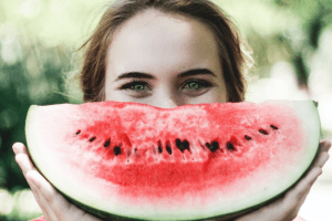Woman enjoying a slice of watermelon on a sunny day.